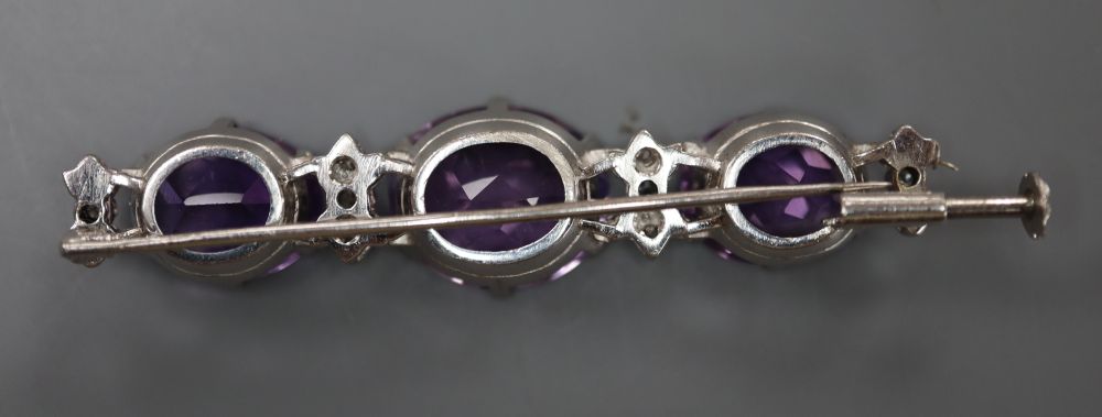 A modern white metal, three stone oval cut amethyst and diamond chip set bar brooch, 55mm, gross 11.1 grams.